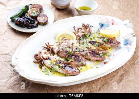 Barbecue tradizionale greco di calamari con erbe e limone come vista dall'alto su una piastra Foto Stock