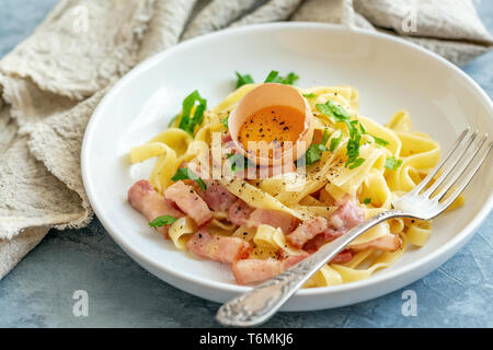 La pasta alla carbonara con tuorlo d'uovo in una piastra bianca. Foto Stock