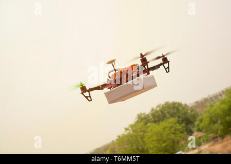 Concetto di assemblati Drone quadcopter offrendo un pacchetto Foto Stock