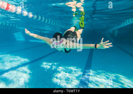 Donna di nuoto in pinne gialle in piscina sott'acqua. La luce diurna