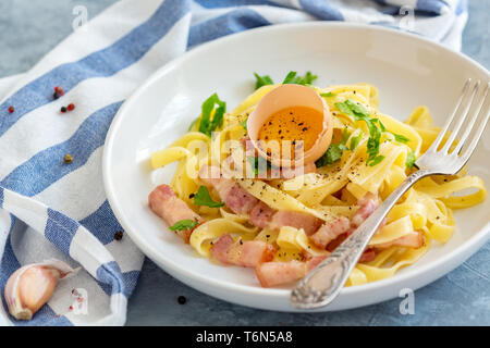 La pasta alla carbonara con tuorlo d'uovo e la forcella nella piastra. Foto Stock