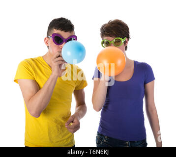 Uomo e donna con occhiali da sole palloncini di soffiatura Foto Stock