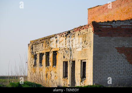 Vecchio mattone sovietica edificio abbandonato. Collassare costruzione in mattoni. Il bianco e il rosso mattone Foto Stock