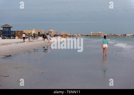 Sarasota, Stati Uniti d'America - 27 Aprile 2018: il tramonto in Siesta Key, Florida con coste oceano costa golfo del Messico sulla spiaggia a riva e giovane donna a piedi da onde Foto Stock