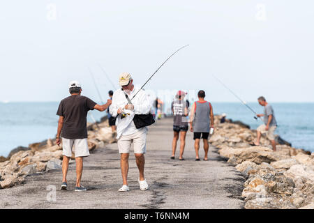 Venezia, Stati Uniti d'America - 29 Aprile 2018: molti uomini permanente di pesca dei pescatori sul molo roccioso in Florida il pensionamento spiaggia cittadina nel golfo del Messico con aste Foto Stock