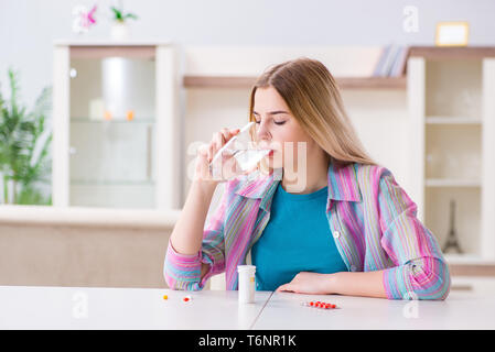 Donna di prendere le pillole per affrontare il dolore Foto Stock