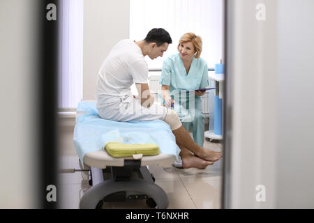 Ortopedico e paziente con gamba bendato in ospedale Foto Stock