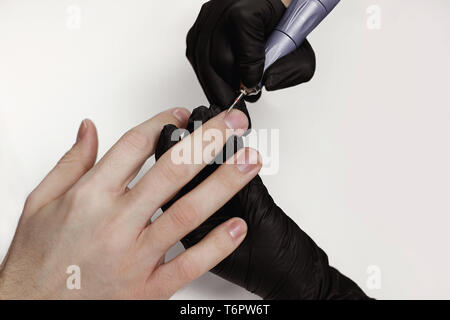 L'uomo sulle procedure nel salone di manicure. Spa, manicure, il master elabora chiodi il macinacaffè. Bel maschio di mani. Foto Stock