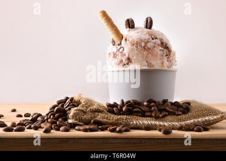 Gelato al caffè Tazza decorata con grani e waffle sul sacco di stoffa su un tavolo di legno. Composizione orizzontale. Vista frontale. Foto Stock