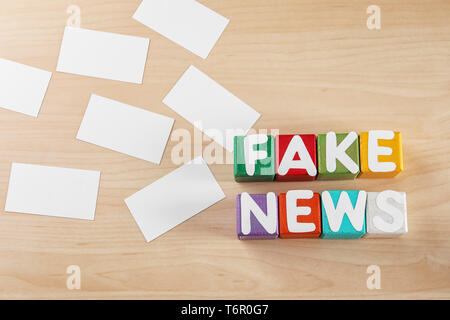 La frase FAKE NEWS realizzati dai cubi con lettere sullo sfondo di legno Foto Stock