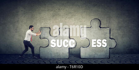 Fiducioso business man spingendo le parti del puzzle di successo Foto Stock