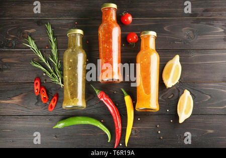 Composizione con salse saporite su sfondo di legno, vista dall'alto Foto Stock