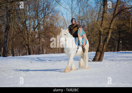 Uomo in tuta di antiche viking riding big White Horse Foto Stock