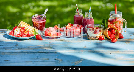 In estate il cibo e le bevande fragole di giardino. Gelato,cialde, frullati, ciotola e punzone, dessert in giardino per un caffè del tempo. Foto Stock