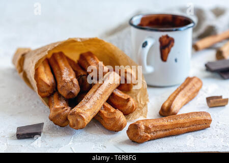 Churros con la cannella e lo zucchero in un sacchetto di carta. Foto Stock