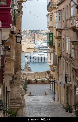 Una vista verso il basso St John Street a La Valletta di fronte a Fort St Angelo e Birgu, con i super yacht Martha Ann lasciando il Grand Harbour Foto Stock