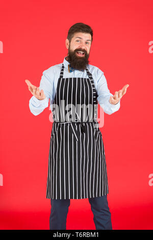 Siete i benvenuti. Uomo Barbuto con gesto di saluto indossando grembiule di bib. Allegro uomo cook con barba e baffi in cucina il grembiule. Elegante uomo cameriere o barista. Un uomo servo. Foto Stock