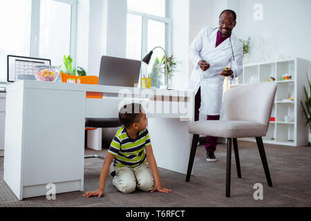 Divertente carino ragazzo giocando in ospedale in visita a padre al lavoro Foto Stock