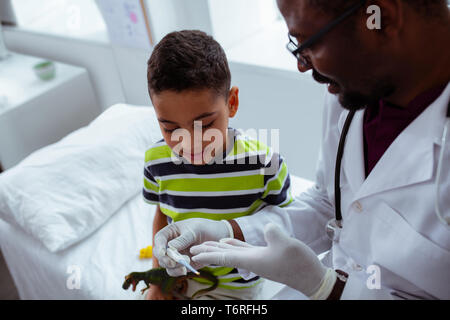 Di carnagione scura bambini medico mostrando little boy termometro Foto Stock