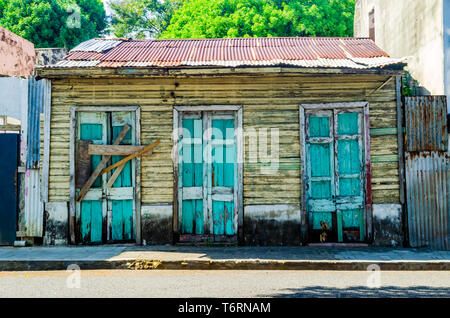 Vecchio abbandonato casa in legno, con il tipico design Dominicana nella zona coloniale di Santo Domingo, il blu e il giallo al coperto con lastre di zinco Foto Stock