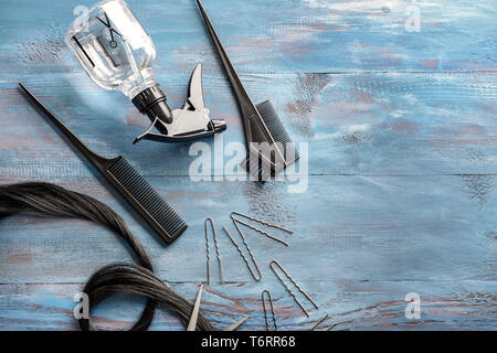 Piano di composizione dei laici con il parrucchiere strumenti e trefolo di capelli neri su sfondo di legno Foto Stock