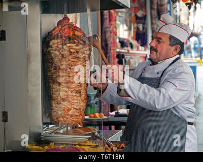 Uno chef fette di carne di Döner da uno spiedo rotante in Istanbul Foto Stock