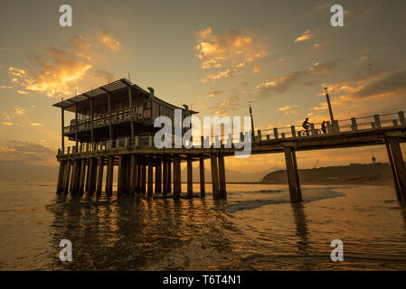 Moyos Pier a Durban, Sud Africa, silhoetted contro il cielo a sunrise. Foto Stock