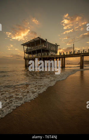 Moyos Pier a Durban, Sud Africa, silhoetted contro il cielo a sunrise. Foto Stock