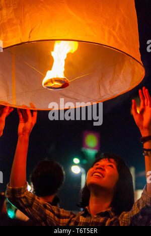 Chiang Mai, Thailandia - Nov 2015: una giovane donna fulmine fino una lanterna per rilasciarla durante il Loy Krathong festival in Chiang Mai Foto Stock