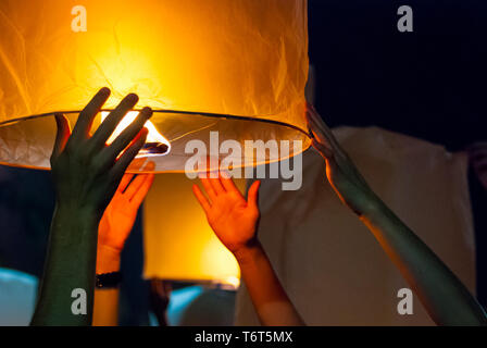 Il rilascio di una luce di lanterna durante il Loy Krathong festival in Chiang Mai, chiudere l immagine di mani Foto Stock