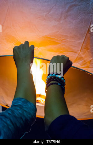 Il rilascio di una luce di lanterna durante il Loy Krathong festival in Chiang Mai, chiudere l immagine di mani Foto Stock
