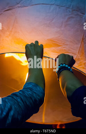 Il rilascio di una luce di lanterna durante il Loy Krathong festival in Chiang Mai, chiudere l immagine di mani Foto Stock