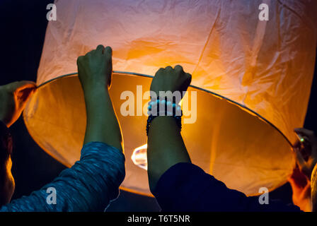 Il rilascio di una luce di lanterna durante il Loy Krathong festival in Chiang Mai, chiudere l immagine di mani Foto Stock