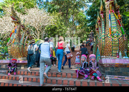 Chiang Mai, Thailandia - DIC 2015: Tribal ragazze vestiti in abiti tradizionali seduti a scale e guardando triste nella parte anteriore del tempio Doi Suthep entranc Foto Stock