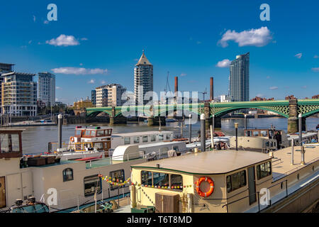 Houseboats lungo il Tamigi a Battersea con Battersea Railway Bridge e Chelsea Harbour sullo sfondo, Londra, Regno Unito Foto Stock