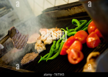 Pollo alla griglia con pomodori e peperoncini rossi sulla graticola Foto Stock