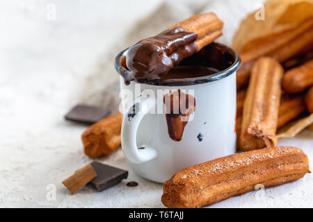 Churros con cannella in tazza di cioccolata calda. Foto Stock