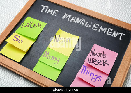 Lavagna con la frase " La gestione del tempo' e colorato sticky notes sul tavolo Foto Stock