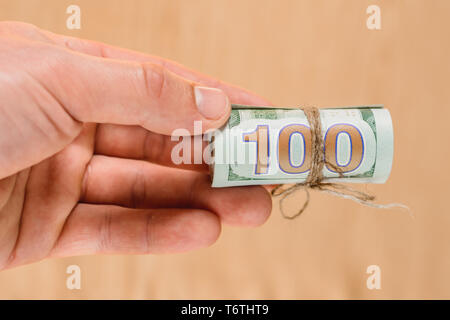 Una mano d'uomo azienda 100 centinaia di banconote, un trasferimento di denaro. 2019 Foto Stock