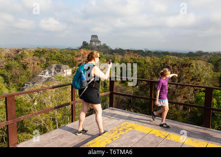 Tikal turisti - famiglia di scattare le foto dei templi rovinati dalla sommità del Mondo Perduto piramide, Mundo Perdido, Tikal rovine maya, Guatemala Foto Stock