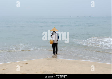 Un uomo locale pesca sulla spiaggia di Jimbaran a Bali, in Indonesia Foto Stock