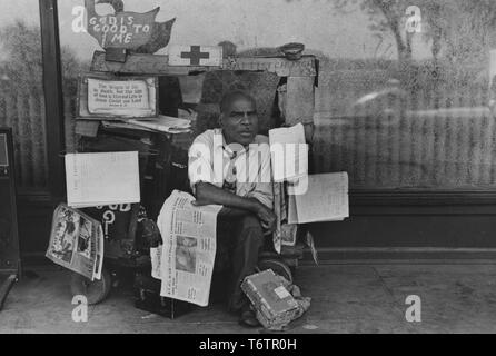 Fotografia di African American uomo seduto sul suo carrello edicola circondato da quotidiani, Memphis, Tennessee, 1938. Dalla Biblioteca Pubblica di New York. () Foto Stock