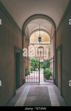 Cortile con un arco e cancellata in ferro battuto in una storica casa italiana a Roma Foto Stock