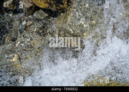 Close-up di acqua da un torrente di montagna sgorga giù sopra rocce Foto Stock