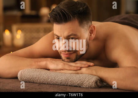Giovane uomo rilassante su lettino da massaggio nella spa salone Foto Stock