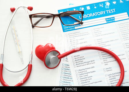 Uno stetoscopio con cuore rosso e gli elenchi delle prove di laboratorio su sfondo bianco. Health care concept Foto Stock