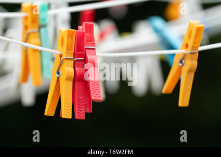 Rosso e giallo abiti colorati pioli su uno stendibiancheria Foto Stock