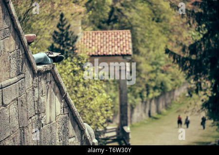 Senior donna prendendo il resto e sun lungo il percorso della storica via di pellegrinaggio dal Sacro Monte o il Sacro Monte di Varese, Italia - Lombardia Foto Stock