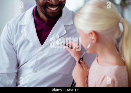 Bionda paziente utilizzando uno stetoscopio giocando con il medico Foto Stock