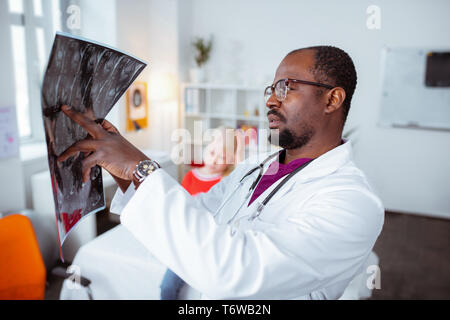 Medico barbuto guardando a raggi x della bimba bionda Foto Stock
